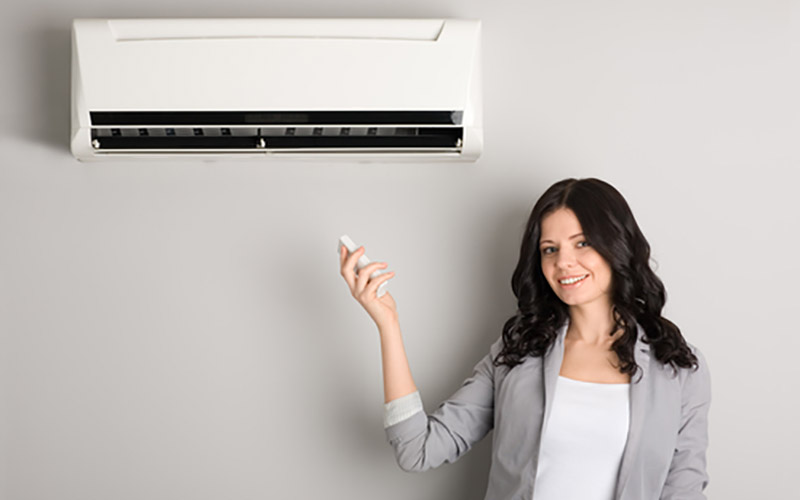 woman turns on ductless air conditioner