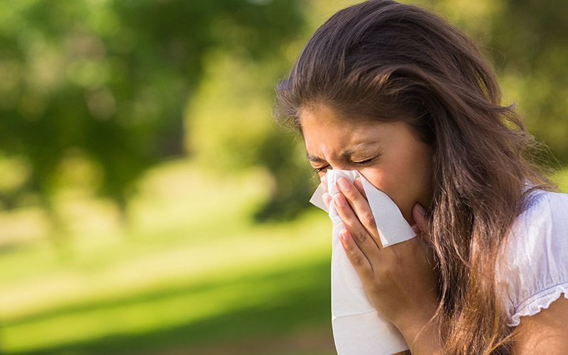 Woman Blowing Nose With Tissue Paper At Park