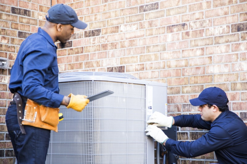 technicians repairing ac unit