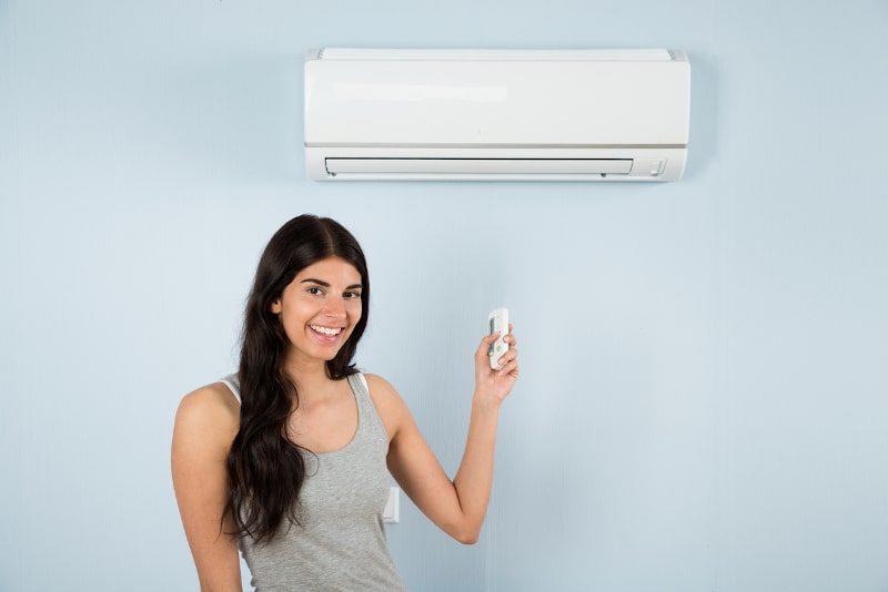 women holding remote to ductless mini-split