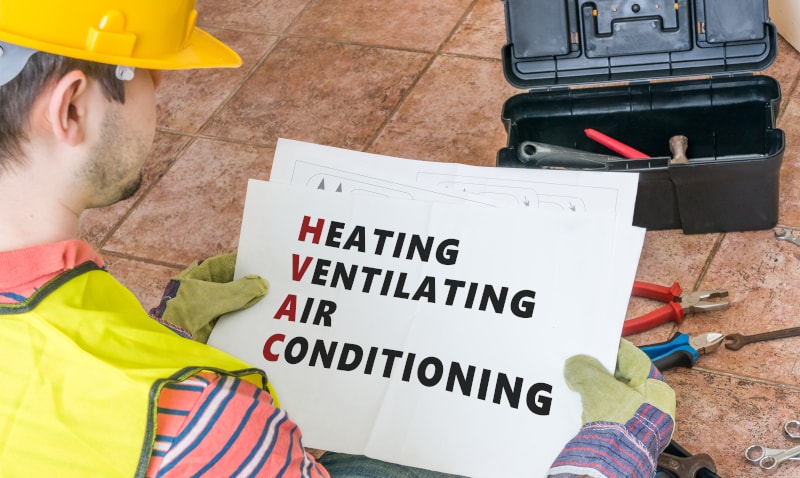 Workman Holding Paper That Says Heating Ventilating Air Conditioning