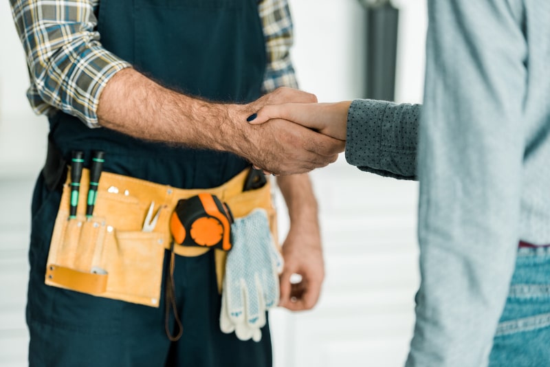 Handshake between contractor in tool belt and client