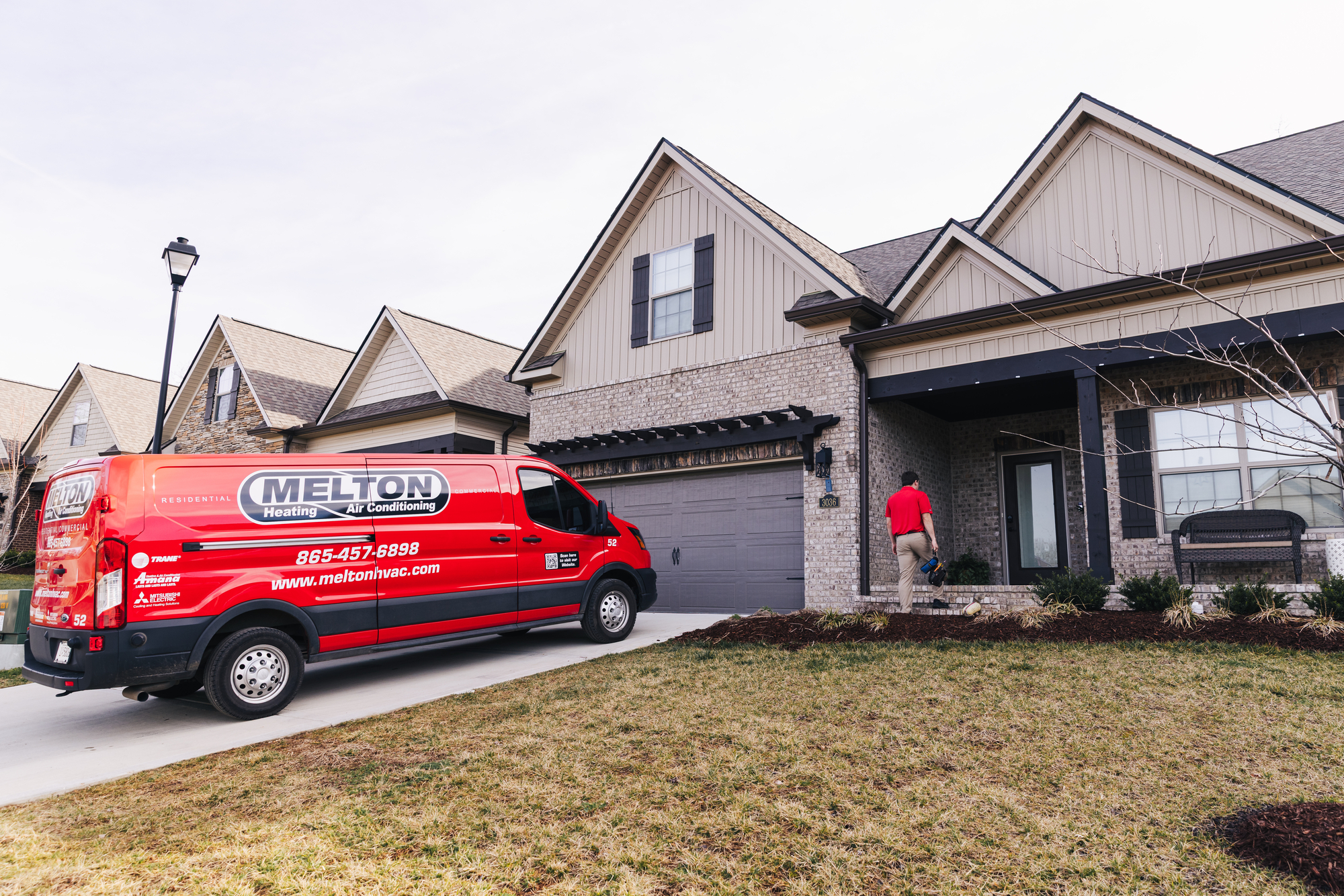 Technician walking up to home with van in driveway